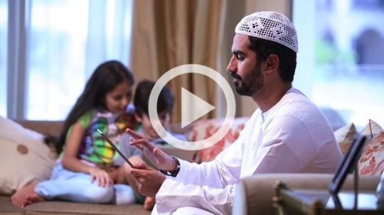 Arab man and kids sitting using their devices|