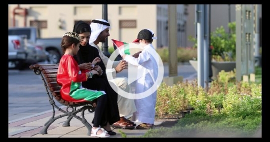 Middle Eastern family sitting together on the bench celebrating the UAE National Day|