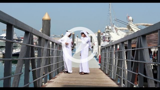 Arab friends standing on the dock talking to each other|