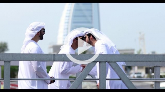Arab men dressed in the traditional UAE attire standing on the dock|