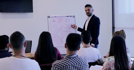 Group of students sitting in the classroom while the professor is teaching|-