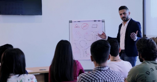 Students in the classroom taking notes|-