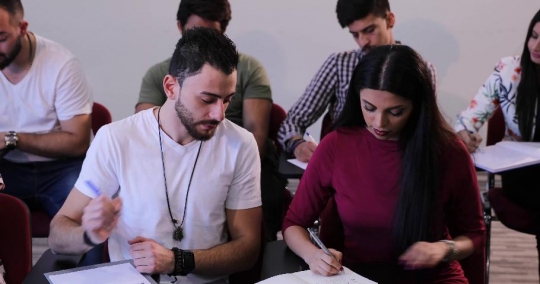 Middle Eastern students sitting together in the classroom writing notes|-