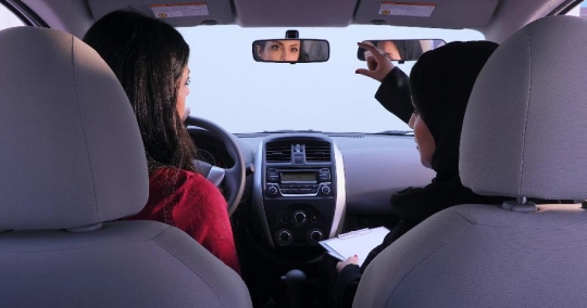 Woman talking to the student in the car about the rear mirror|-