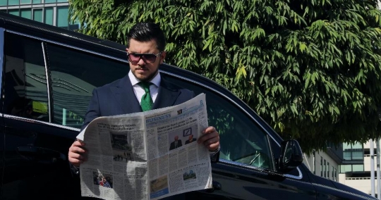 Western Businessman leaning on the car reading the newspaper |-