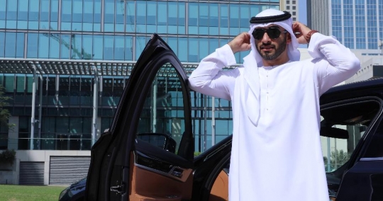 Middle Eastern Businessman standing by his car fixing his kandoura|-