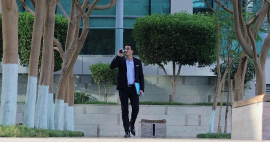 Middle Eastern Businessman drinking coffee walking|-
