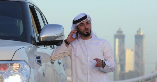 Businessman leaning on his car talking on the phone|-