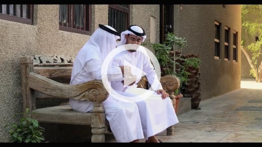 Arab father and son sitting on the bench talking to each other|