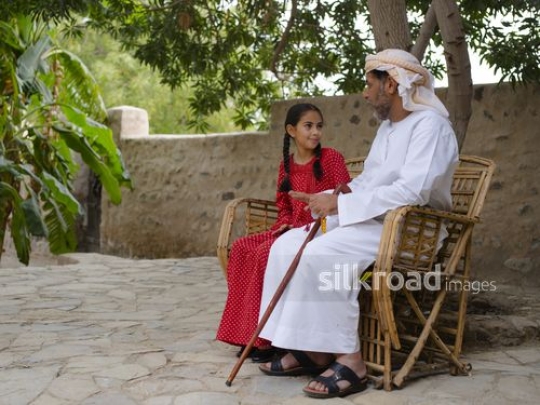 Girl with grandfather sitting outside|-