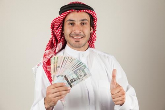 an arabian man holding saudi arabia riyal and showing thump up