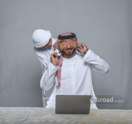 Son covering eyes of his father while working