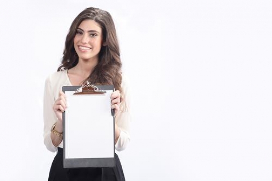 Smiling woman holding blank clipboard
