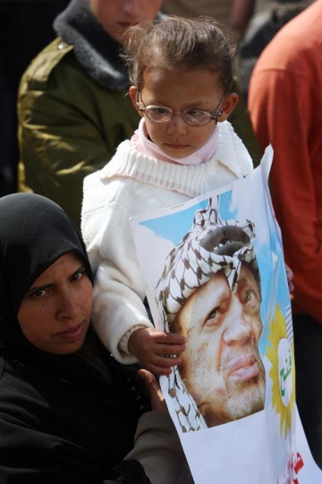 little girl with glasses holding yaser arafat poster
