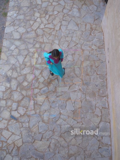 Girl playing hopscotch outside|-