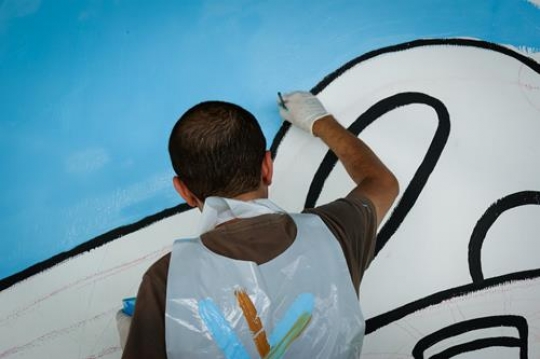 male volunteer painting the wall of kindergarten