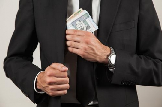 businessman putting money in his jacket pocket