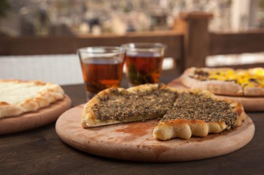 two cups of tea with a pizza and manakish zaatar and cheese