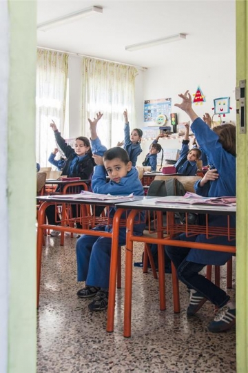 group of schoolchildren at classroom during a lesson raising hands