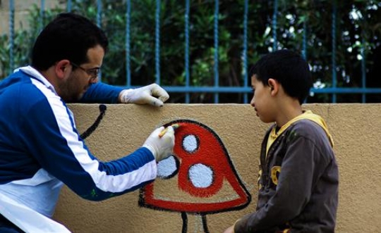 father with his son painting the wall of kindergarten