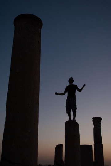 man standing on a roman corinthian columns in umm qais