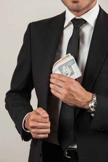 businessman putting money in his jacket pocket