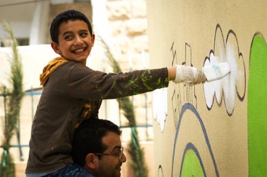 happy father and his son painting a wall of kindergarten