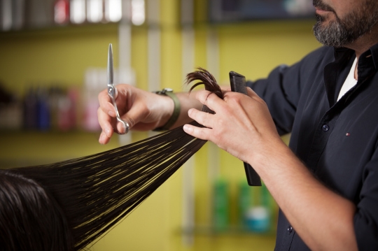 Hair stylist cutting the woman's hair|