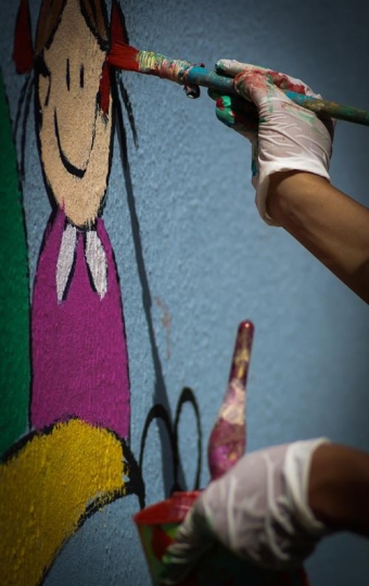 human hand painting the wall of kindergarten