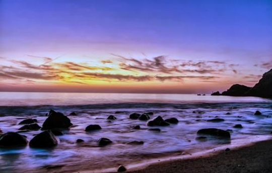Sunset lanscape, purble sky over a rocky seashore.