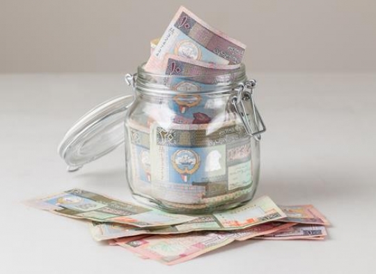 glass jar filled of kuwaiti dinars