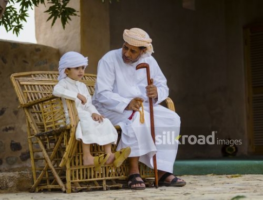 Grandfather sitting with grandson on bench|-