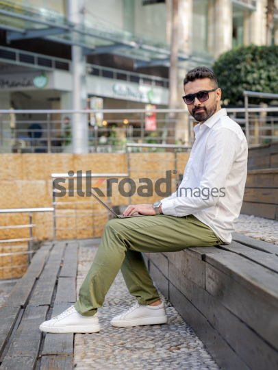 Arab Man Working Outdoors with Laptop in Amman's Abdali Boulevard