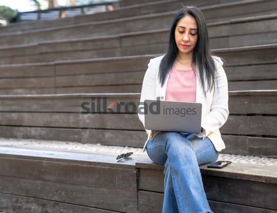 Arab Woman Working on Laptop Outdoors in Jordan's Al Abdali Boulevard
