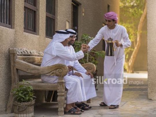 Arab son offering grandfather some coffee|-