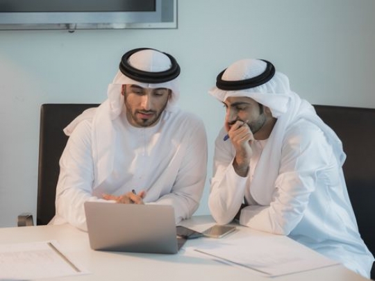 Arab men during a meeting at the office wearing the traditional attire|-