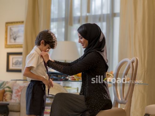 Middle Eastern woman getting her son ready for school|