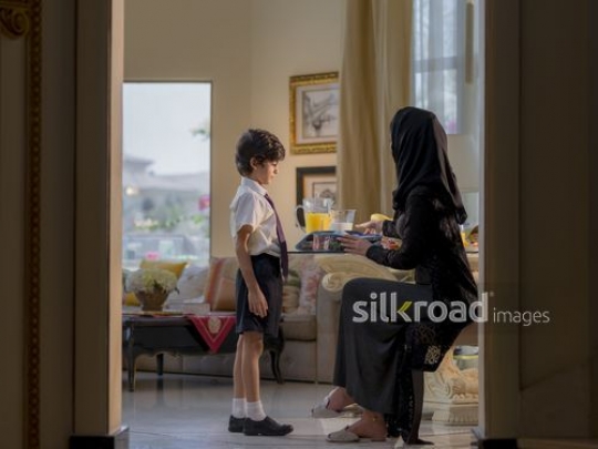Middle Eastern woman getting her son ready for school|