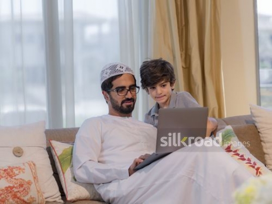 Middle Eastern man and young boy sitting together on the couch|