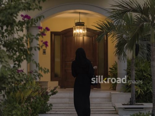 Middle Eastern woman walking towards her house|