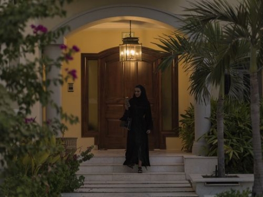 Arab woman leaving the house while on her phone|-