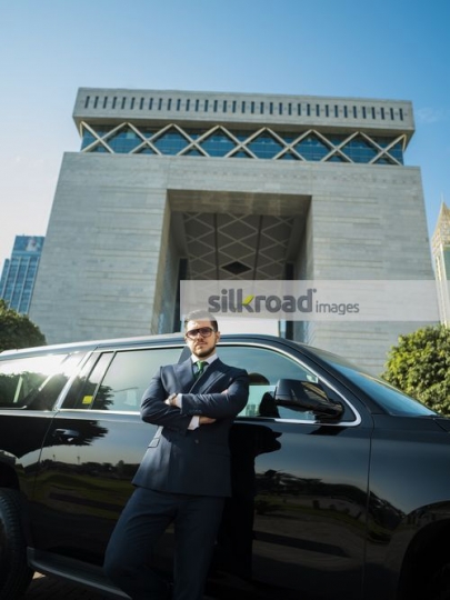 Young Western Businessman leaning on the car hands crossed|