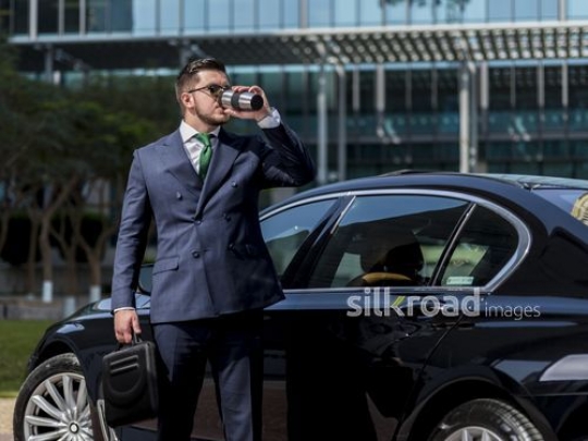 Western Businessman drinking from his travel mug|-