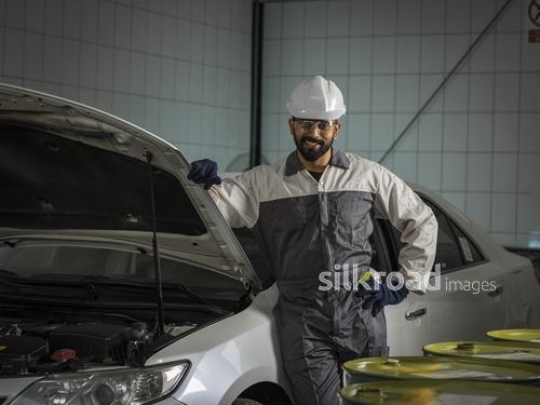 Mechanic Worker in uniform standing next to the car|-