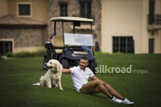 Arab man sitting with his dog on the grass|-