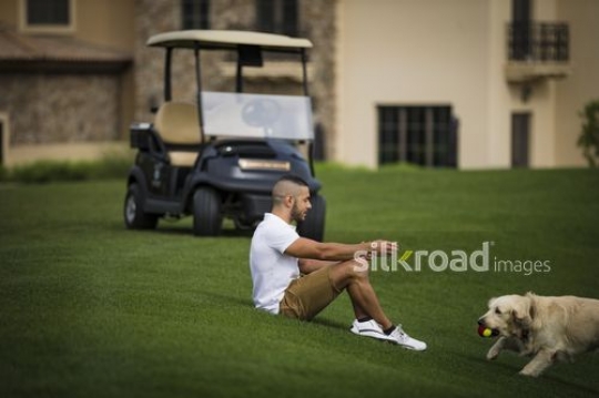 Middle Eastern man playing fetch with the dog|-
