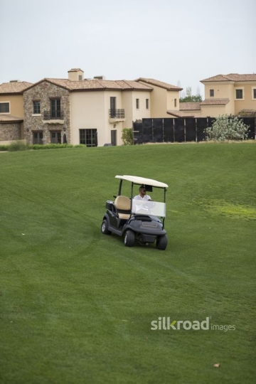 Young Middle Eastern man driving around the resort with the Golf Cart|-