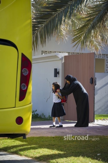 Arab mother helping her daughter with her school bag|-