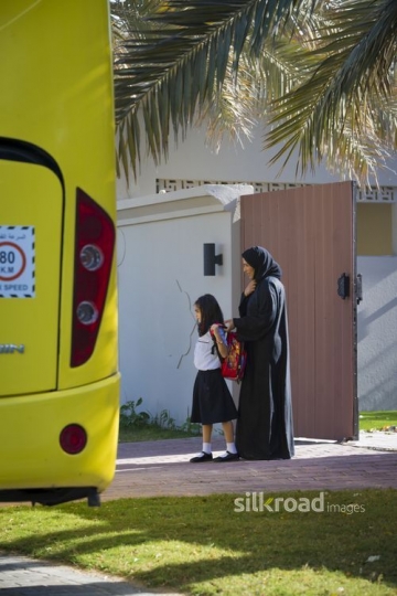 Middle Eastern mother giving her daughter the school bag|-