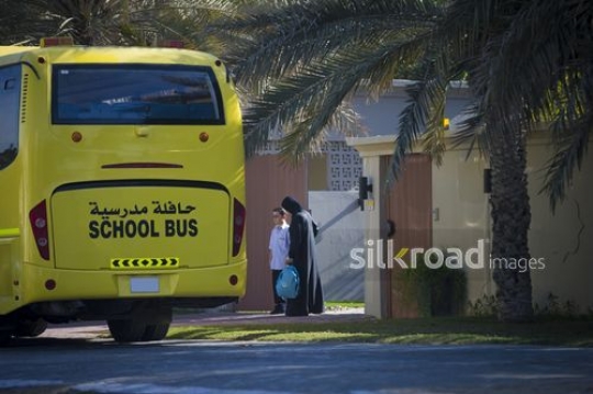 Arab mother dropping her kid outside for the school bus|-